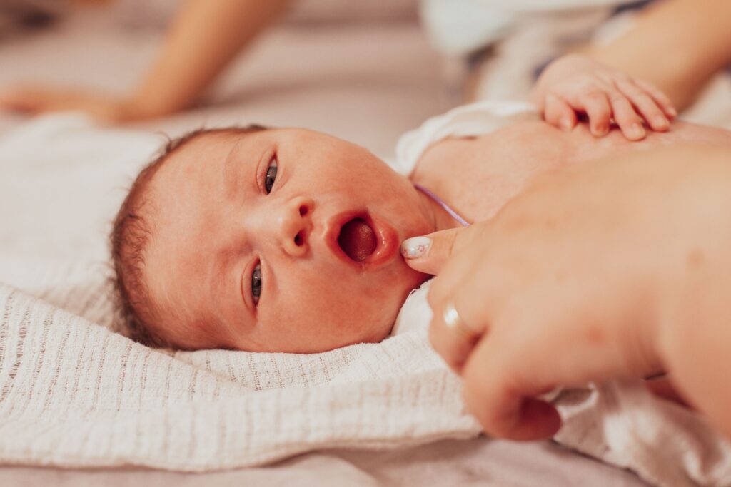 Finger pulling down infant's lip